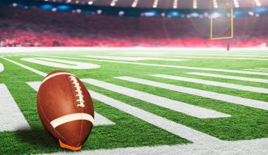 American football stadium with goal post and ball on tee ready for field goal kick. Focus on foreground ball with shallow depth of field on background and copy space.