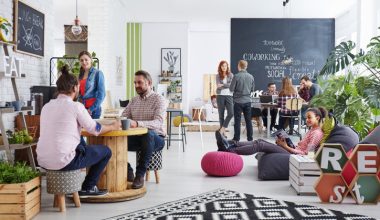 A group of coworkers gathering for a meeting in a contemporary office conference room.