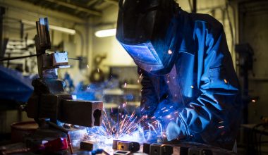 A person welding an item while wearing protective gear.