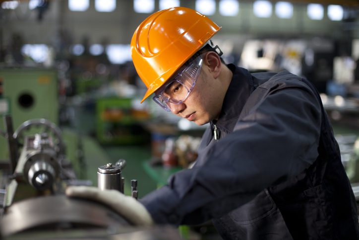 A man in a hard hat operating a machine at a construction site.

