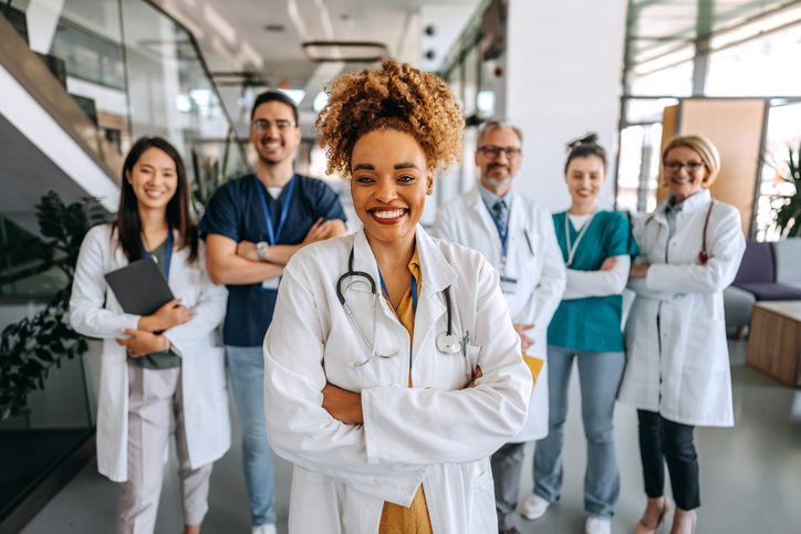 Group of six smiling healthcare professionals in a medical facility.