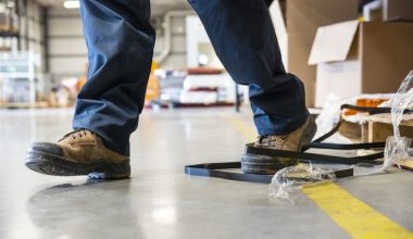Person stepping on black strapping on a warehouse floor.