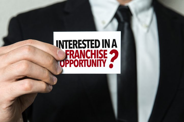 Man holding interested in a Franchise Opportunity card.