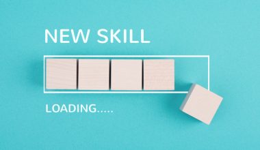 Photo of a teal background with wooden blocks arranged like a progress bar and one block offset to the right, with white text reading “NEW SKILL” above and “LOADING…..” below.
