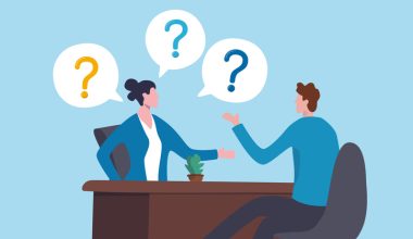 Illustration of two office workers seated across a desk in conversation, with speech bubbles containing question marks above them, symbolizing a discussion, interview, or Q&A session; blue background, brown desk, and small potted plant on the tabletop.